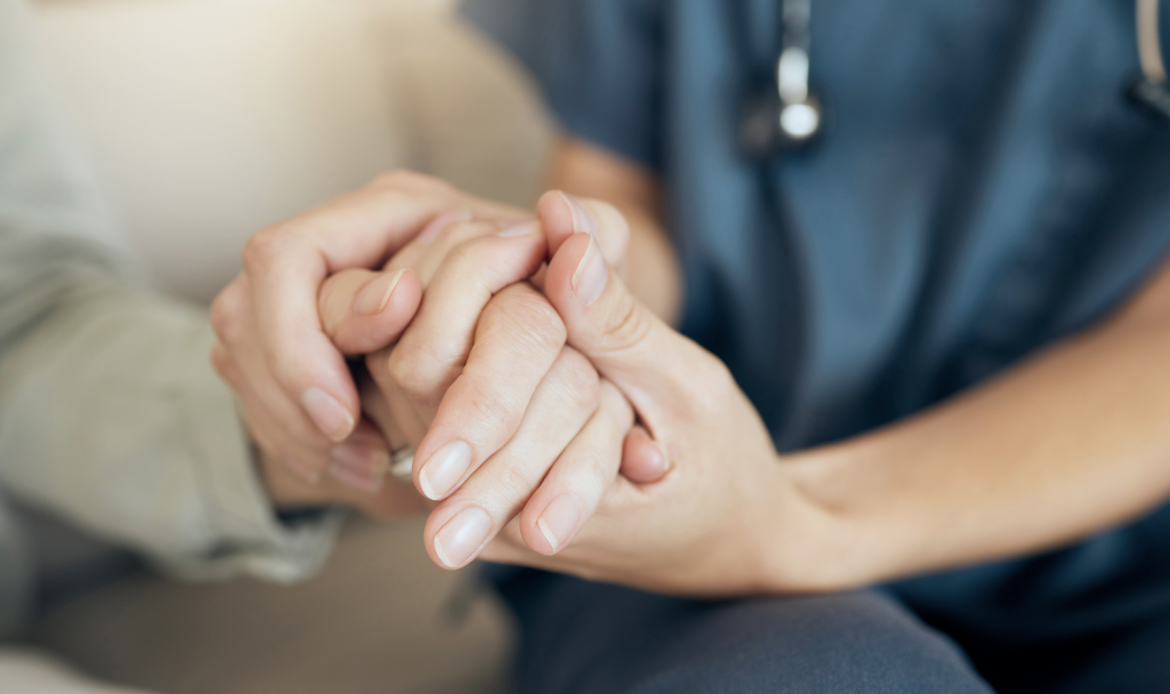Private duty nurse holding patients hand for post-op visit at home for in-home care recovery.
